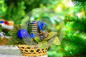 New Year`s decor. Spruce twigs and a round blue glass ball in a wicker basket