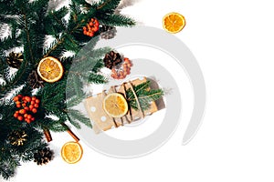 New Year's decor on a white background with branches of a green fir, pine cones and slices of dry orange and gift