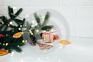 New Year's decor on a white table with branches of a green Christmas tree, pine cones and slices of dry orange and