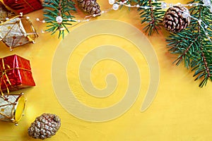 New Year's decor on a yellow table - fir branches, cones, garlands and Christmas toys