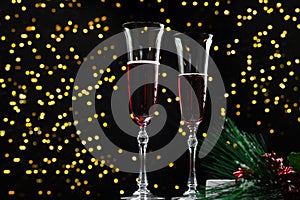 New Year's Eve 2022 - Champagne glass on a dark background with a side of garlands. A classic alcoholic beverage