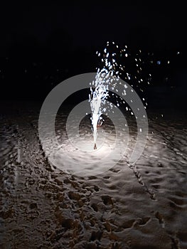 A New Year's fireworks display is lit, standing in the snow. Sparklers