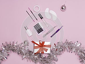 New year`s flatley. Tools for eyelash extension on a pink background, top view. Patches, artificial eyelashes, brushes, glue,