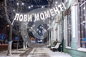 New Year's garlands and benches on a snow-covered city street.