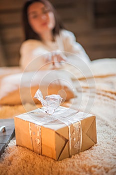 New Year`s gift close-up, the girl reaches out for a gift. Scandinavian style bedroom interior under Christmas. Rustic Textured Wo