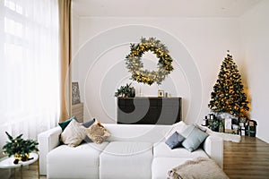 New Year`s interior. Decorated Christmas tree with gifts. Wreath of spruce with garland. Christmas decorations