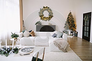 New Year`s interior. Decorated Christmas tree with gifts. Wreath of spruce with garland. Christmas decorations