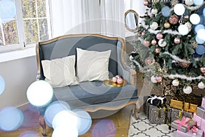 New Year`s interior with Ñhristmas-tree decorations, balls and lights. Comfortable blue sofa with pillows in the room. Classics