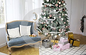 New Year`s interior with ÃÂhristmas-tree decorations, balls and lights. Gifts under the tree. Comfortable blue sofa with pillows