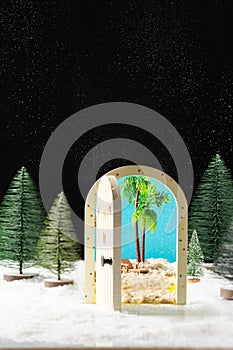 New Year`s magic. Christmas tree, miniature door overlooking the beach and palm trees.