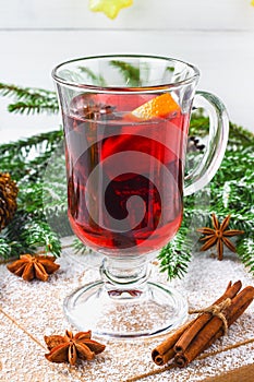 New Year's mulled wine in a glass on the background of twigs, candles and garlands.