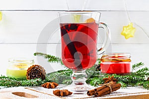 New Year's mulled wine in a glass on the background of twigs, candles and garlands.