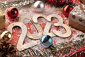 New Year's number 2023 made of wooden numbers on red paper with Christmas balls, gift boxes, fir branches