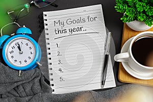 New year`s resolution concept. Notepad on black home office desk. photo