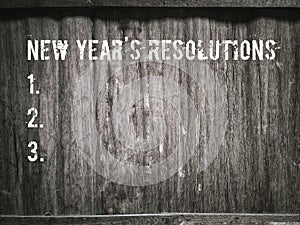 NEW YEAR'S RESOLUTIONS text written on wooden wall background. Stock photo.