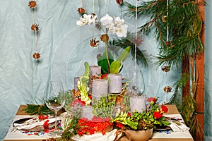 New Year\'s still life, thick candles among viburnum berries, spruce branches, white orchid flowers and glass goblets