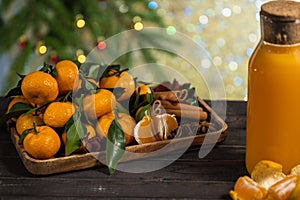 New Year`s tangerines with leaves on a wooden tray with spices star anise and cinnamon and tangerine juice on the background of