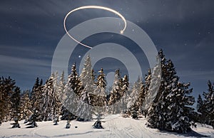 New Year's trail from a star in the night sky as a background for snow-covered trees in a beautiful valley