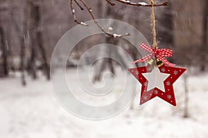 New Year`s white-red toy in the form of a star hangs on a tree on the street in winter in snowy weather. Christmas concept