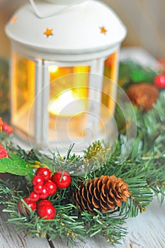 New Year`s wreath from a fir-tree on a white wooden background and a candle in a white candlestick.