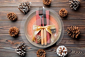 New Year set of plate and utensil on wooden background. Top view of holiday dinner decorated with pine cones. Christmas time