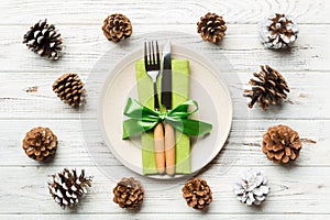 New Year set of plate and utensil on wooden background. Top view of holiday dinner decorated with pine cones. Christmas time