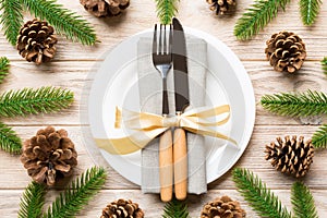 New Year set of plate and utensil on wooden background. Top view of holiday dinner decorated with pine cones. Christmas time