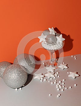 New year shiny decorations and glasses on orange and gray background. Minimal celebration concept