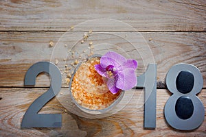 New Year 2018, spa set on wooden table, coconut and bath salt, flower of orchids and black stones for hot massage