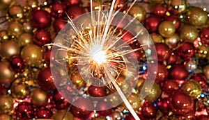 New year sparkler lighting up amazing red yellow and gold decorative balls