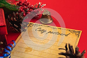 New year still life, christmas bell, fir branches and postcard on red background