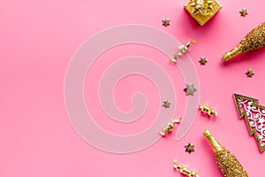 New Year symbols - tree, champagne, decorations - on pink background top-down frame copy space