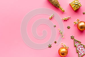 New Year symbols - tree, champagne, decorations - on pink background top-down frame copy space