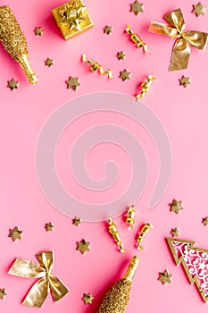 New Year symbols - tree, champagne, decorations - on pink background top-down frame copy space