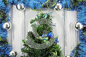 New year theme christmas tree with blue and green decoration and silver balls on white stylized wood background