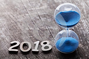 New year 2018 time concept. Hourglass or sandglass on rustic wooden table.