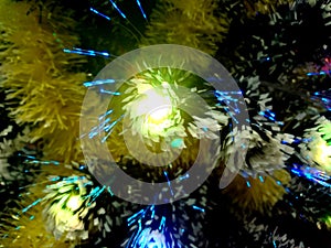 New Year tinsel with neon lights on a Christmas tree closeup