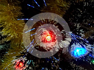 New Year tinsel with neon lights on a Christmas tree closeup