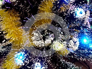 New Year tinsel with neon lights on a Christmas tree closeup