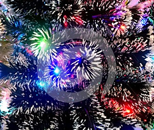 New Year tinsel with neon lights on a Christmas tree closeup