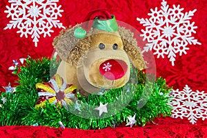 new year toy dog surrounded by decorative Christmas elements and fir branches on red background