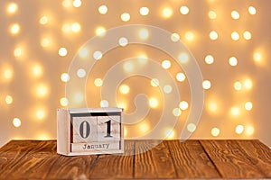 New year, wooden calendar january 1 on wooden background and lights background