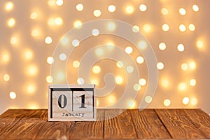 New year, wooden calendar january 1 on wooden background and lights background