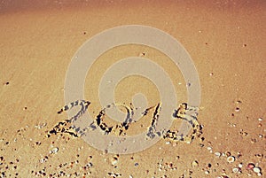 New year 2015 written on sandy beach. retro filtered image.