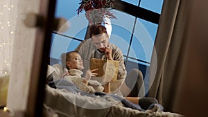 New Year. Young Couple Reading Book In Bed.