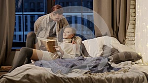 New Year. Young Couple Reading Book In Bed.