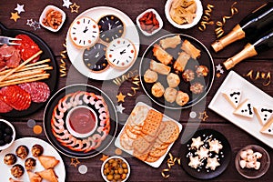 New Years Eve appetizer table scene. Overhead view on a dark wood background.