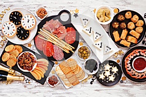 New Years Eve appetizer table scene. Overhead view on a white wood background.