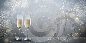 New years eve concept with two glasses of bubbly champagne on a silver grey colored design background.