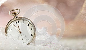 New Years eve countdown. Minutes to midnight on an old fashioned pocket watch, bokeh snowy background